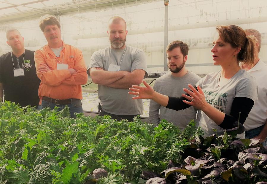 Tawnya Sawyer co-owner of The Aquaponic Source and students learning about deep water culture in an indoor aquaponic farm.